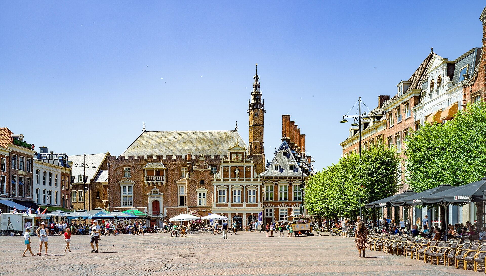 A Grote Markt de Haarlem num dia de sol, com a prefeitura antiga, terraços e gente
